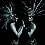 Cara Romero photograph Arla Lucia featuring figures in Aztec headdresses and calavera face paint honoring Indigenous traditions