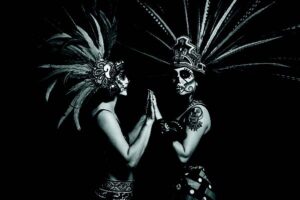 Cara Romero photograph Arla Lucia featuring figures in Aztec headdresses and calavera face paint honoring Indigenous traditions