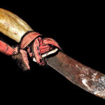Ifugao tribal knife with curved animal tooth handle and forged iron blade wrapped in leather