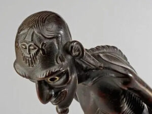 Marquesan tiki stone sculpture showing seated ancestral figure carved from dark volcanic basalt