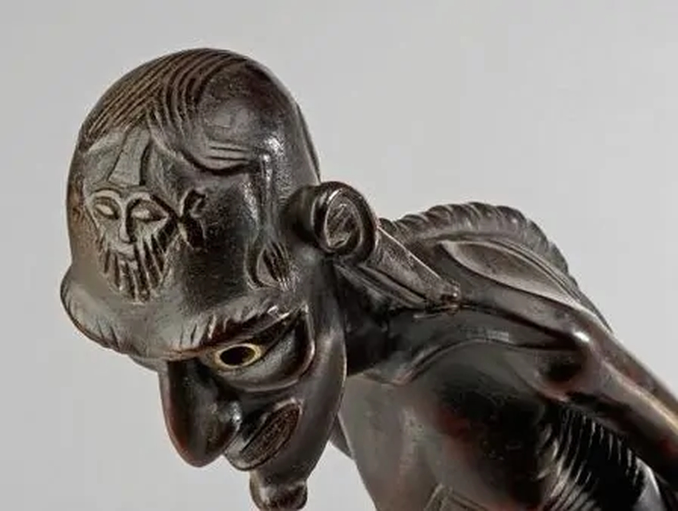 Marquesan tiki stone sculpture showing seated ancestral figure carved from dark volcanic basalt